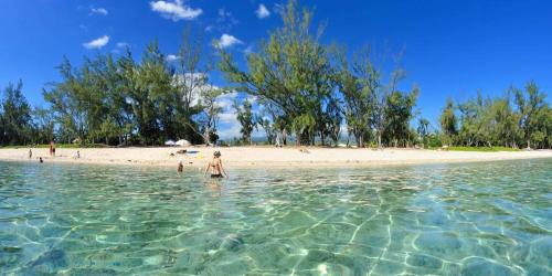 a person standing in the water at a beach at Grand studio varangue lagon La Saline in Saint-Paul