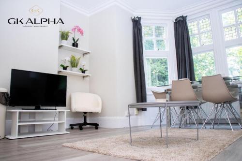 a living room with a tv and a table and chairs at Modern 2-Bed Apartment with Wi-Fi & Parking Near Royal Berkshire Hospital & Reading Station in Reading