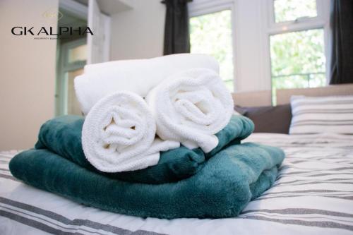 a pile of towels sitting on top of a bed at Modern 2-Bed Apartment with Wi-Fi & Parking Near Royal Berkshire Hospital & Reading Station in Reading