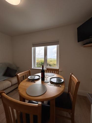 a dining room table with a bottle of wine on it at An Cat Dubh - Luxury Apartment in Dingle