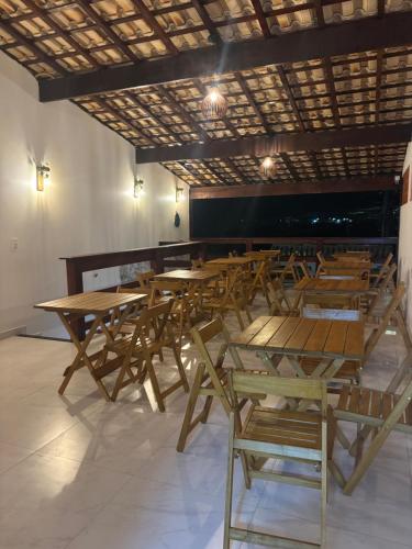 a group of wooden tables and chairs in a room at Pousada Beatriz - Búzios in Búzios