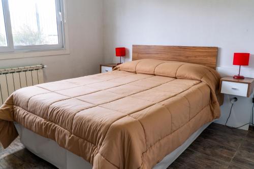 a bed in a bedroom with two lamps on two tables at Femiba in El Calafate