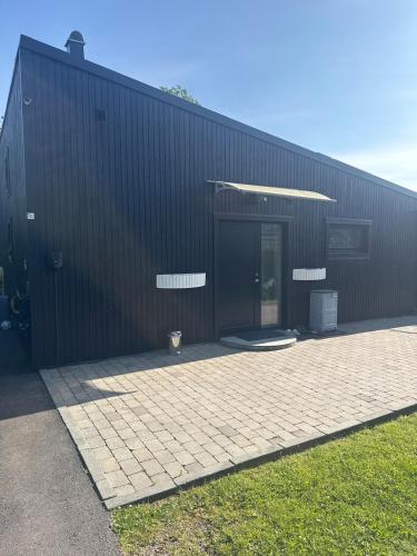 a black building with a door and a patio at Blackrock in Herräng