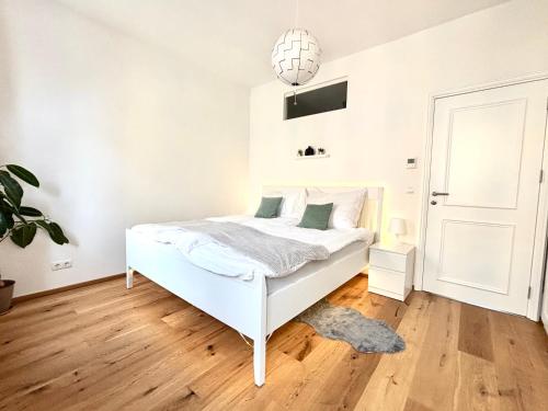 1 dormitorio con cama blanca y lámpara colgante en Vienna Nest, central and quiet with balcony and garden, self check-in, en Viena