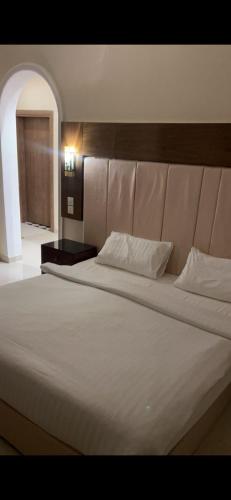 a large bed with white sheets and a head board at منتجع شاطي الاحلام in Yanbu