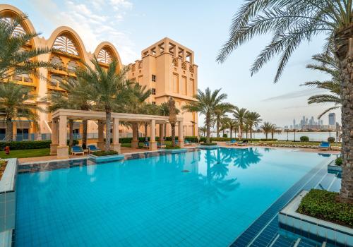 a large swimming pool in front of a building at Simply Comfort Vacation Homes Rental Luxury Beachfront Villa with Private Pool on Palm Jumeirah near Atlantis in Dubai