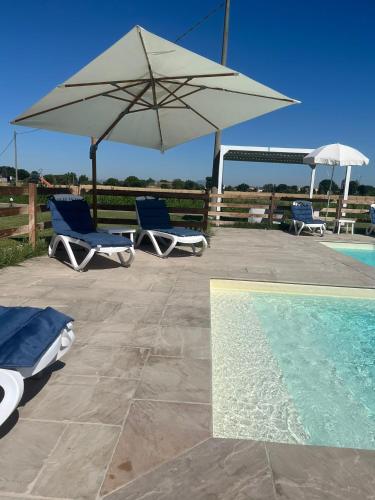 two chairs and an umbrella next to a swimming pool at Luci di Assisi B&B Wellness in Assisi