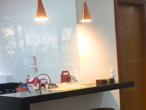 a kitchen counter with a sink and two lights at Mar de Itaparica 2 quartos, apenas 450 metros da praia in Vila Velha