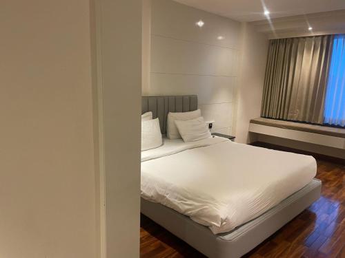 a bedroom with a bed with white sheets and a window at Blu O Shiv Ganga River View in Varanasi