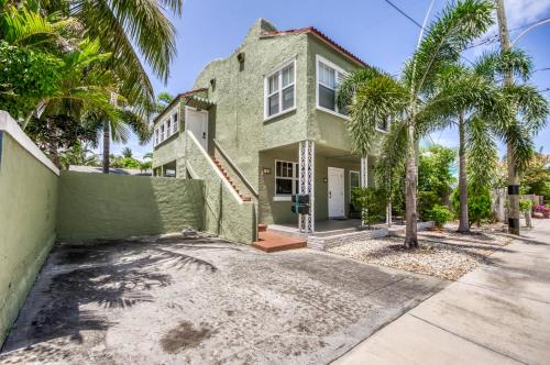 a green house with palm trees in front of it at Historic Home near the water - perfectly walkable spot! in Lake Worth