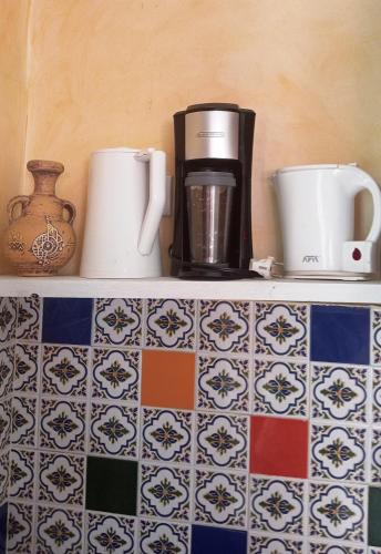 a shelf with two coffee cups and a vase at Dar El Amen Appartements in Mahdia