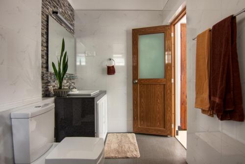 a bathroom with a toilet and a wooden door at Aquahills in Kandy
