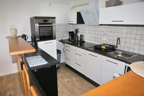 een keuken met witte kasten en een zwart aanrechtblad bij Ferienhaus Domus in Xanten