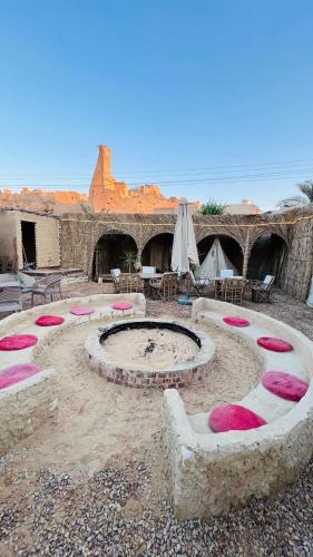 a patio with a fire pit in the desert at Muhra Camp in Siwa