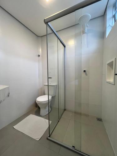 a glass shower in a bathroom with a toilet at Regis Hotel I in Registro