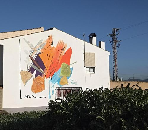 a mural on the side of a white building at Apartamento Fuente del Genil. in Fuente Vaqueros