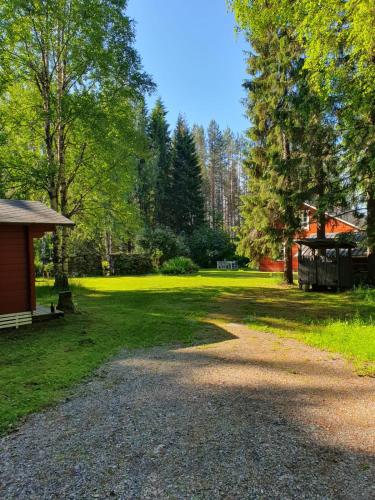 a gravel road leading into a yard with trees at Villa Lahtela in Kajaani