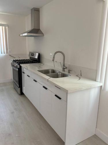 a white kitchen with a sink and a stove at San Marino guest house in Los Angeles