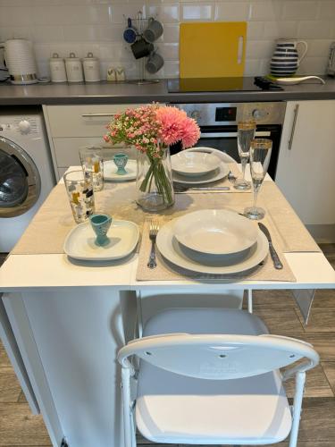 a kitchen with a table with plates and a vase of flowers at Rose Lodge in Saint Albans