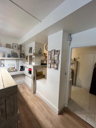 Il comprend une grande cuisine avec des murs blancs et du parquet. dans l'établissement Cosy et Charmant Appart 80 m2 au Panier - Vieux Port, à Marseille
