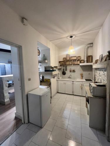 Il comprend une grande cuisine avec des placards blancs et du carrelage. dans l'établissement Cosy et Charmant Appart 80 m2 au Panier - Vieux Port, à Marseille