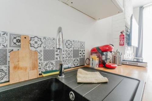 a kitchen with a sink and a black counter top at L'Estival, T2 à 5min de la gare avec WIFI in Lens