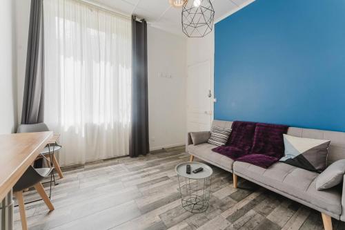 a living room with a couch and a blue wall at L'Estival, T2 à 5min de la gare avec WIFI in Lens