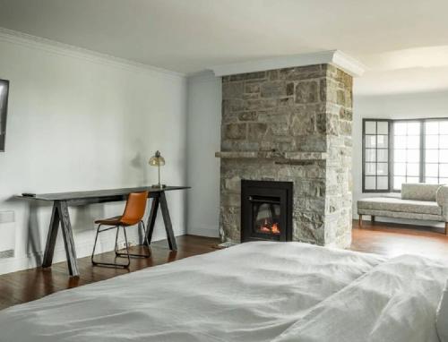 a bedroom with a stone fireplace and a bed at Domaine Fairbanks in La Malbaie