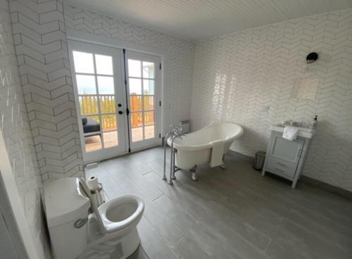 a bathroom with a tub and a toilet and a sink at Domaine Fairbanks in La Malbaie