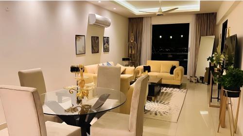 a dining room and living room with a glass table and chairs at Elysium Tower Premium Hotel Serviced Apartments Islamabad in Islamabad