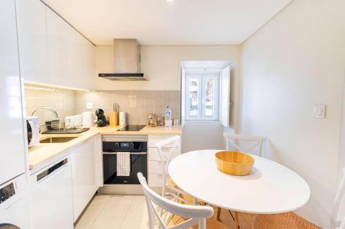 una cucina bianca con tavolo e sedie bianchi di Discover Lisbons History - Stylish apartment in Alfama a Lisbona