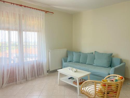 a living room with a blue couch and a table at Cosy Stay Apartment with Sea View in Kalandra
