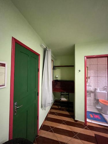 a bathroom with a green door and a sink at Pousada Morango das Palmas in Praia de Palmas