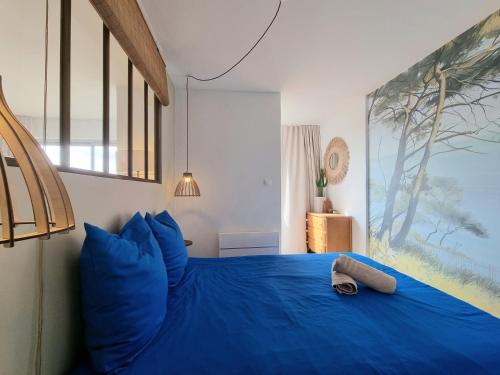 a bedroom with a blue bed with a large window at L'Horizon doré, Vue mer et dunes, Plage à pied in Saint-Hilaire-de-Riez