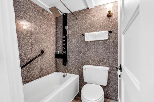 a bathroom with a white toilet and a bath tub at Aztec Ocean Resort in Seaside Heights