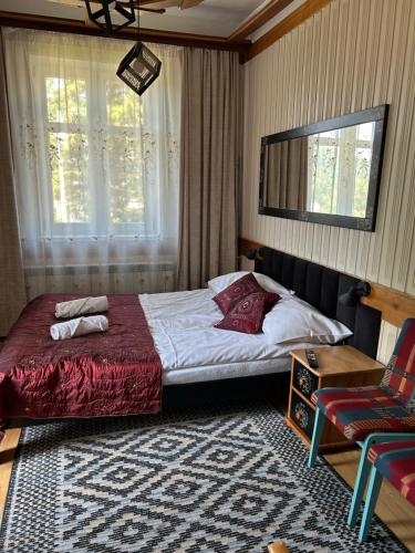 a bedroom with a large bed and a chair at Willa Halinówka in Krynica Zdrój