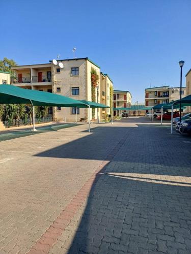 an empty parking lot with a large green canopy at Wanansha Apartments in Gaborone