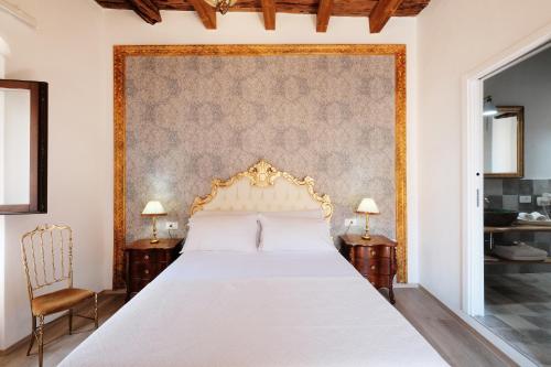 a bedroom with a white bed with a gold headboard at Il mio tempo al Castello in Castelsardo