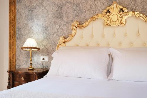 a bedroom with a white bed with a gold headboard at Il mio tempo al Castello in Castelsardo