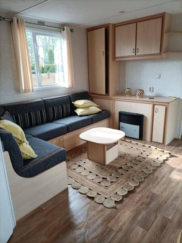 a living room with a couch and a table at Ibiza chalet in natuurlijke omgeving in Bergen op Zoom