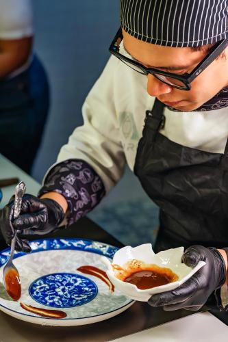 a man in black gloves is holding a plate with sauce at Burú Nature Hotel in Leticia