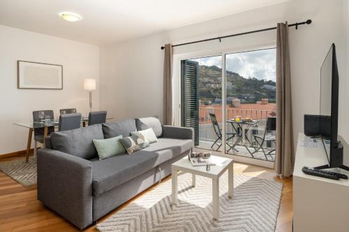 a living room with a couch and a table with a balcony at Alta Vista Caniço by An Island Apart in Santa Cruz