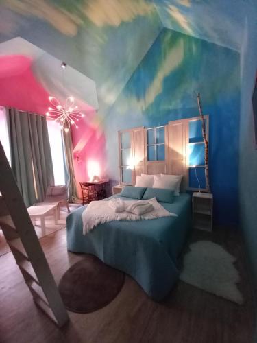a bedroom with a blue bed and a colorful ceiling at Aux quatre coins du monde in Champvoux