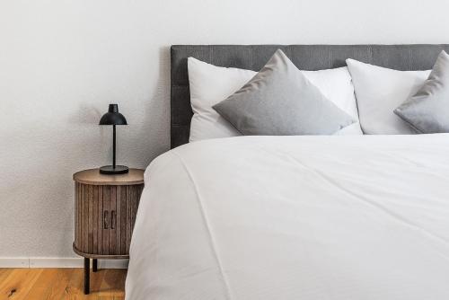 a white bed with pillows and a lamp on a table at CITY-LOFT 2 !Gratis parken, Free parking! in Schaffhausen