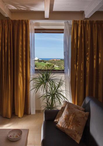 a living room with a couch and a large window at Hotel Raffael PHG in Putzu Idu