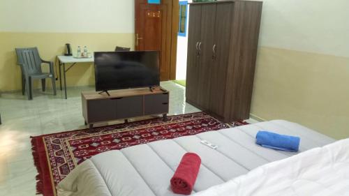 a bedroom with a bed with a tv and a red sock at SALEM House Hostel Nizwa in Nizwa