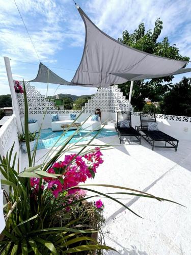 a patio with a white umbrella and some flowers at Nueva Vista INN in Cruz de Huanacaxtle