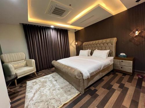 a bedroom with a large bed and a chair at Gold Crest Mall Prestigious Suites with Balcony by CityScape in DHA Lahore in Lahore