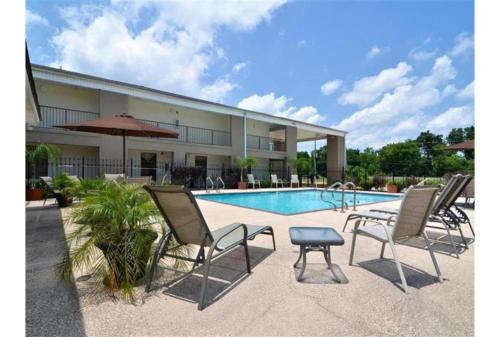 a group of chairs and a table next to a pool at Motel 6-Mobile, AL in Tillmans Corner