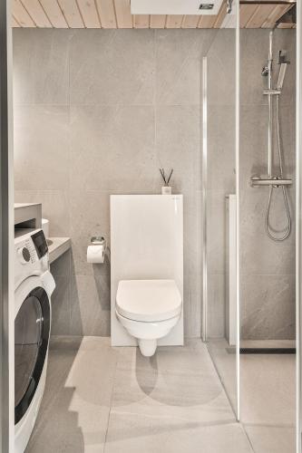 a bathroom with a toilet and a washing machine at Rorbuleilighet Lysøysundet 1G in Henningsvær
